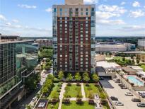 A high-rise building overlooks manicured grounds, a parking deck, and an outdoor pool on a sunny day at 285 Centennial Olympic Park Nw Dr # 809, Atlanta, GA 30313