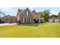 Two-story brick home features a well-manicured lawn, charming front porch, and a separate two-car garage at 739 E Mays E Rd, Stockbridge, GA 30281