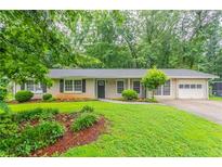 Charming one-story home featuring a well-manicured lawn and attached garage at 1496 Indian Forest Ct, Stone Mountain, GA 30083
