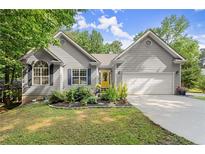 Charming home featuring a gray exterior, well-manicured lawn and landscaping, attached garage, and a bright yellow front door at 2730 Samples Rd, Cumming, GA 30041