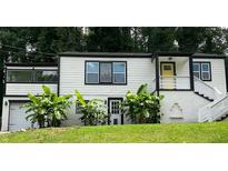 Charming home with a striking black and white exterior, highlighted by vibrant banana trees in the front yard at 2170 Beecher Sw Cir, Atlanta, GA 30311