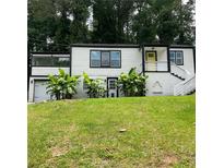 Charming two-story home boasts lush landscaping and a welcoming yellow front door at 2170 Beecher Sw Cir, Atlanta, GA 30311