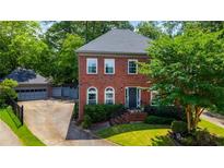 Charming brick two-story home with lush landscaping, a detached garage, and a welcoming front entrance at 2870 Livsey Woods Dr, Tucker, GA 30084