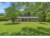 Charming single-story brick home with a well-maintained lawn and mature trees at 676 Smith Store Rd, Covington, GA 30016