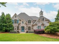 Beautiful stone home featuring a turret, symmetrical facade, arched windows, and manicured lawn at 165 Ansley Way, Roswell, GA 30075