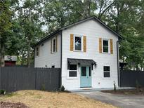 Charming two-story home with white siding, wood shutters, gray fence and inviting light blue front door at 5090 Lorraine Pl, Forest Park, GA 30297