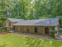 Charming brick home with arched windows, lush lawn, and surrounded by mature trees at 5632 Stillwater Ct, Stone Mountain, GA 30087