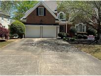 Charming two-story brick home with a well-manicured lawn, mature trees, and a two-car garage at 2612 Peterboro Row, Marietta, GA 30062
