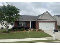 Charming single-story brick home featuring a well-manicured lawn, a two-car garage, and lovely front yard landscaping at 804 Village Pl, Loganville, GA 30052