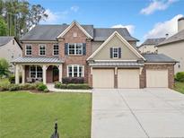 Traditional brick home with a three-car garage, landscaped yard, and covered front porch at 508 Highland Drive Dr, Woodstock, GA 30188