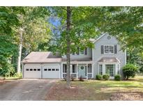 Charming two-story home with a light-colored exterior, a three-car garage, and a welcoming front yard at 802 Bluff Pl, Woodstock, GA 30188