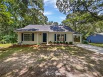 Charming single-story home with light-colored siding, black shutters and a well-maintained front yard, surrounded by mature trees at 978 Monopoly Dr, Lawrenceville, GA 30046