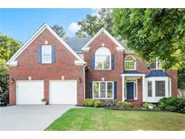 Charming two-story brick home featuring a well-manicured lawn and attached two-car garage at 5204 Tealing Ne Dr, Roswell, GA 30075