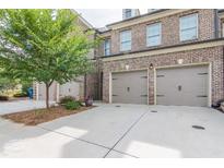 Brick townhome showcasing a two-car garage and concrete driveway at 5535 Bright Cross Way, Suwanee, GA 30024
