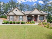 Charming single story home boasts brick and stone exterior with a well-manicured lawn and inviting covered porch at 6460 Valley Crossing Way, Cumming, GA 30028