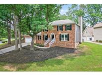 Charming two-story brick home with mature trees, a manicured lawn, and a classic architectural style at 4619 Villa Chase Ne Dr, Marietta, GA 30068