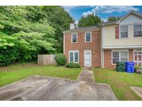 Charming townhome with a brick facade, green lawn, and a private driveway with mature trees at 1696 Hunting Creek Dr Se, Conyers, GA 30013