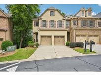 Two-story townhome with attached two-car garage, neutral brick facade, and manicured front lawn at 1636 Caswell Pkwy, Marietta, GA 30060