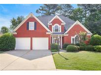 Charming red brick home featuring a two-car garage, manicured lawn, and lush landscaping at 1250 Parkview Nw Ln, Kennesaw, GA 30152
