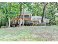 Traditional brick home with green shutters, surrounded by mature trees and a spacious front yard at 1592 Walkway Ct, Lilburn, GA 30047