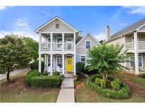 Charming two-story home featuring a welcoming porch, a bright yellow door, and manicured landscaping at 240 Daisy Cir, Mcdonough, GA 30252