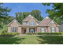 Charming two-story home with a beautifully landscaped front yard, stone, and brick facade at 3320 Pleasant Springs Dr, Cumming, GA 30028