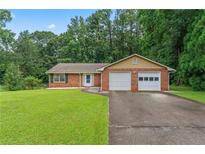 Charming brick ranch-style home featuring a two-car garage and a well-manicured front lawn at 1738 Sherry Ln, Jonesboro, GA 30236