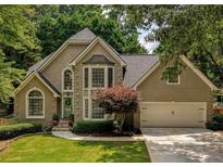 Charming home with a well manicured lawn, colorful shrubbery, and a two-car attached garage at 9975 Groomsbridge Rd, Johns Creek, GA 30022