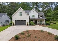 Charming two-story white farmhouse with a dark gray garage door and well-manicured landscaping at 2490 S Carroll S St, Villa Rica, GA 30180