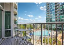 Relaxing balcony area with seating overlooking a sparkling community pool and lush landscaping at 943 Peachtree Ne St # 902, Atlanta, GA 30309