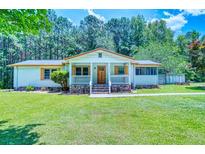 Charming single-story home with a well-maintained lawn, inviting front porch, and beautiful surrounding trees at 5160 W Chapel Hill Rd, Douglasville, GA 30135