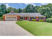 Charming single-story brick home with a well-manicured lawn and colorful landscaping, plus a 2 car garage at 3550 Miller Farms Ln, Peachtree Corners, GA 30096