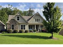 Charming home featuring a stone facade, covered porch, manicured lawn, and mature landscaping at 37 Grand Georgian Ne Ct, Cartersville, GA 30121