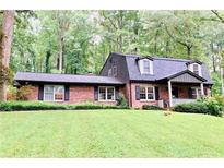 Charming brick home with a lush green lawn, mature trees, and a welcoming front porch at 1050 Lake Charles Dr, Roswell, GA 30075