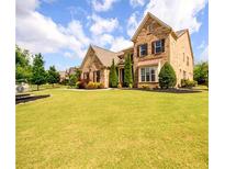 Lovely brick home featuring manicured lawn, beautiful landscaping, and shuttered windows at 6110 Read Rd, Suwanee, GA 30024