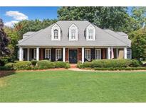 Charming single-story home boasts a manicured lawn, a brick porch, and classic architectural details at 501 Avery Creek Pointe, Woodstock, GA 30188