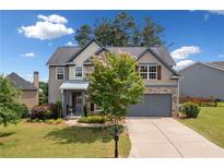 Charming two-story home with stone accents, gray siding, well-manicured lawn and a two car garage at 115 Greenbrier Way, Canton, GA 30114