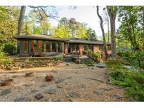 Expansive backyard with mature landscaping, a brick home and a deck that overlooks lush greenery at 1850 Winchester Trl, Brookhaven, GA 30341