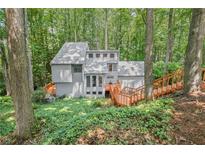 View of the exterior of a multi-story home nestled in a wooded lot with a wooden deck and stairs at 1279 Colony Pl, Marietta, GA 30068