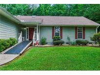 Charming single story home featuring green siding, red shutters and door, and landscaped front yard at 1920 Daves Creek Trl, Cumming, GA 30041