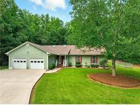 Charming single-story home with a well-manicured lawn, mature tree and a two car garage at 1920 Daves Creek Trl, Cumming, GA 30041