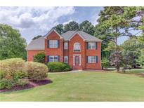Charming brick two-story home with well-manicured lawn, garden beds, and classic design features at 3082 Biltmore Woods Dr, Buford, GA 30519