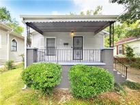 Charming one-story home with covered porch, wrought iron railing, and neatly manicured landscaping at 571 Grant Sw St, Atlanta, GA 30315