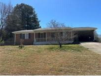 Charming single-story brick home with a covered front porch and a convenient carport on a sunny day at 726 Shoreline Se Trl, Conyers, GA 30094