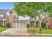 Charming brick home with a two-car garage, well-manicured lawn and mature trees providing shade at 909 Pine Cove Dr, Lilburn, GA 30047