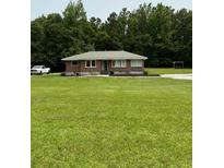 Charming brick home features a sprawling lawn and a backdrop of lush trees at 6900 Rockland Rd, Stonecrest, GA 30038