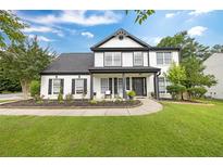 Beautiful two-story home with black trim, white siding, manicured lawn, and a welcoming front porch at 8320 Mayfern Dr, Fairburn, GA 30213