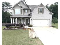 Charming two-story home featuring a landscaped yard, inviting front porch, and a convenient two-car garage at 124 Gorham Gates Ct, Hiram, GA 30141