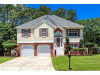 Charming two-story home features a brick-and-stucco facade, complemented by a well-manicured lawn and a two-car garage at 5414 Sweetsprings Sw Dr, Powder Springs, GA 30127