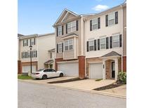View of townhome with attached garages and white car in driveway with beautifully maintained exteriors at 920 Society Sw Cir, Atlanta, GA 30331